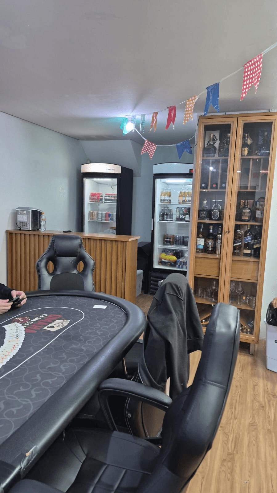 O bar do clube: geladeiras de cerveja e refrigerante e a cristaleira retroiluminada com destilados e taças