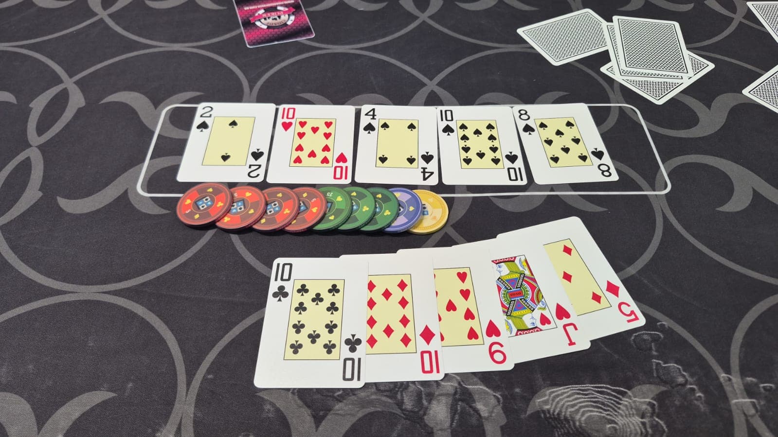 Mão feita na mesa do clube: as cinco cartas do jogador abertas embaixo do board
