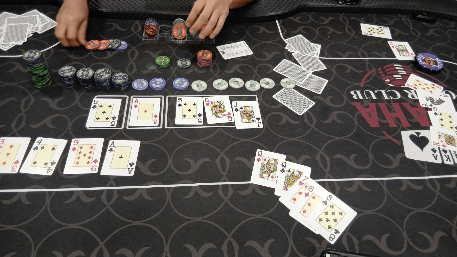 Showdown numa mesa de Omaha: três mãos de cinco cartas abertas em volta do board, com as pilhas de fichas no meio